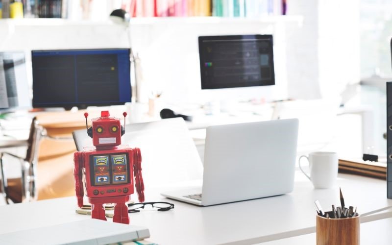 Desk with laptop and a red toy robot