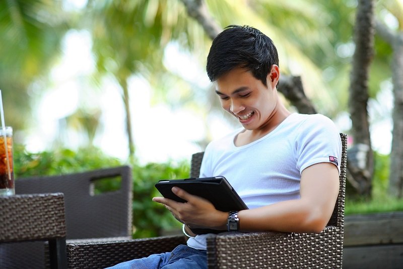 Happy user of a laptop sitting outside.