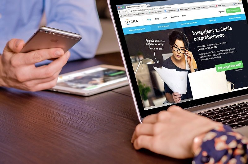 Closeup of meeting across table with mobile phone, tablet and laptop.